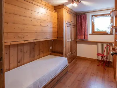a room with a bed in a wooden wall at Casa La Montanina, a due passi dal centro di Cortina in Cortina dʼAmpezzo