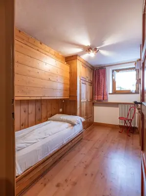 a bedroom with a bed in a room with wooden walls at Casa La Montanina, a due passi dal centro di Cortina in Cortina dʼAmpezzo