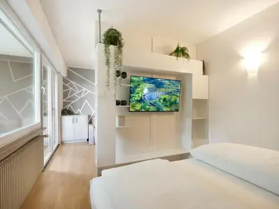 a bedroom with a bed and a tv on a wall at Central Palm Studio with free Parking in Merano