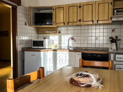 a kitchen with a wooden table and a kitchen with white appliances at Casa Tone in Predazzo