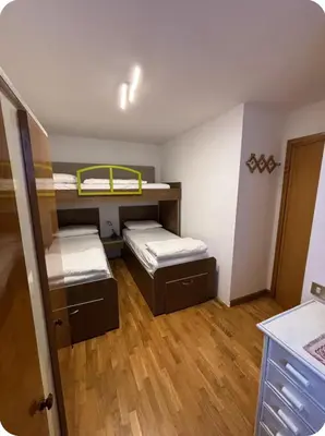 a small room with two bunk beds and wooden floors at Appartamento Villa Lucia in Moena