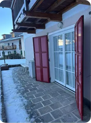 a room with red doors and a bench on a patio at Appartamento Villa Lucia in Moena