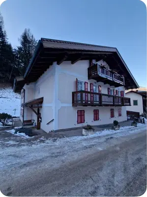 a large white building with red windows and balconies at Appartamento Villa Lucia in Moena