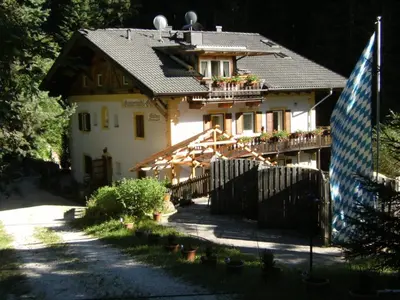 a house with a fence and a flag in front of it at Privatzimmer Gassermühle in Eggen