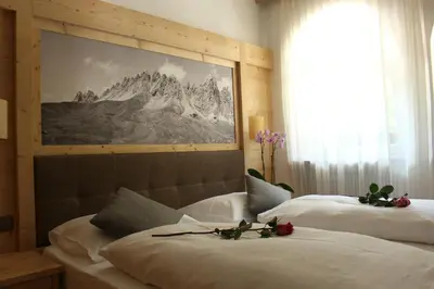 two beds in a hotel room with flowers on them at Residence Frea in Selva di Val Gardena