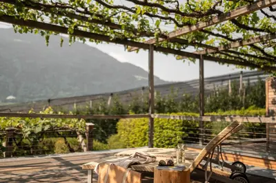 a table and chairs on a patio with a view of a mountain at Pergola Residence in Lagundo