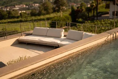 a couch is sitting next to a swimming pool at Pergola Residence in Lagundo