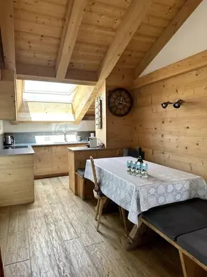 a kitchen with a table in a room with wooden walls at Attico Bellavista in Cortina dʼAmpezzo