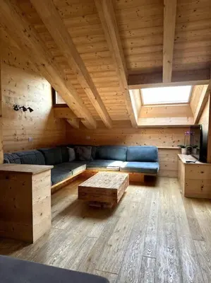 a room with a blue couch in a wooden room at Attico Bellavista in Cortina dʼAmpezzo