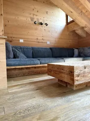 a living room with a blue couch in a wooden room at Attico Bellavista in Cortina dʼAmpezzo