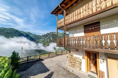a building with a balcony with a view of the mountains at Casa di Sere in Pieve di Livinallongo