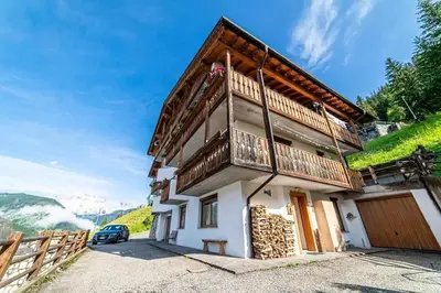 a house in the mountains with a car parked in front at Casa di Sere in Pieve di Livinallongo