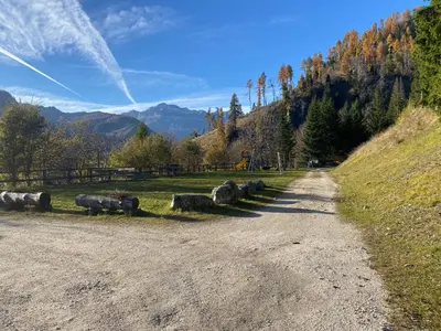 a dirt road next to a field with bales of hay at Casa di Sere in Pieve di Livinallongo