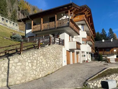 a house with a balcony on top of a stone wall at Casa di Sere in Pieve di Livinallongo