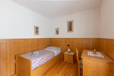 a small bedroom with a bed and a wooden floor at Dolomites Apartment Finestra sul Civetta in Alleghe