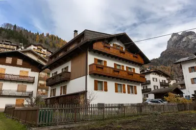 a white house with wooden balconies in a village at Dolomites Apartment Finestra sul Civetta in Alleghe