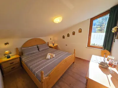 a bedroom with a bed with a teddy bear on it at Sogno sulle Dolomiti - Alpine Stay Apartments in Moena