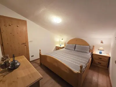 a bedroom with a bed and a wooden table at Sogno sulle Dolomiti - Alpine Stay Apartments in Moena