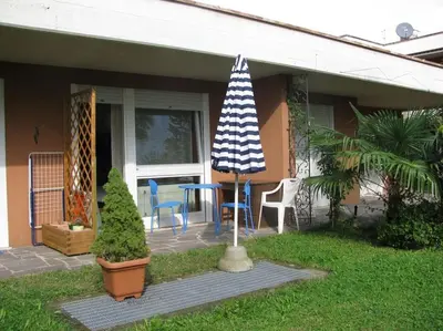 a patio with a table and chairs and an umbrella at Kleine Wohnung, großer Garten! in Merano