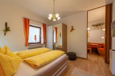 a bed with yellow sheets on it in a room at Ferienhof Franzelin in Termeno
