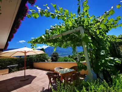 a table and chairs on a balcony with a field of flowers at Ferienhof Franzelin in Termeno