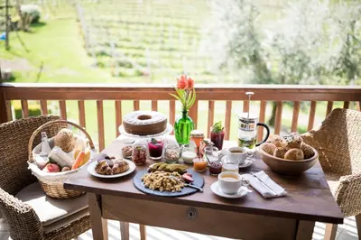 a table with breakfast food on a balcony at Weingut Weidlhof - Suite & Breakfast - Vacation for wine lovers in Caldaro