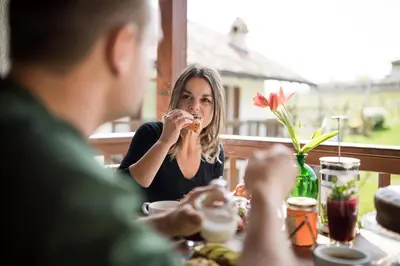 a man and a woman sitting at a table eating food at Weingut Weidlhof - Suite & Breakfast - Vacation for wine lovers in Caldaro