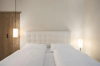 a white bedroom with two white beds and two lights at Weingut Weidlhof - Suite & Breakfast - Vacation for wine lovers in Caldaro