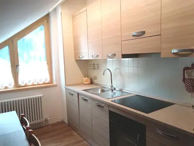 a kitchen with wooden cabinets and a sink and a window at Appartamento 2 Residenza RODODENDRO in Campitello