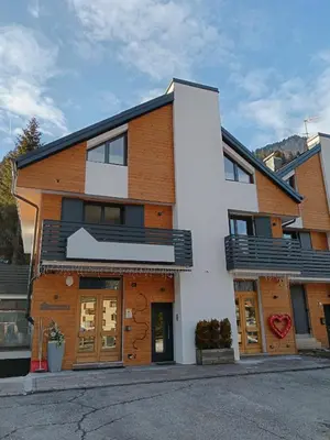 a white building with wooden doors on a street at Appartamento 2 Residenza RODODENDRO in Campitello