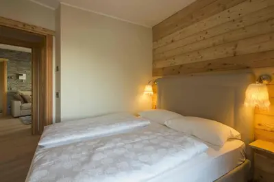 a bedroom with a white bed with a wooden wall at Residence Aspen in Arabba