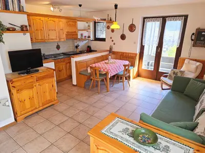 a kitchen and a living room with a table at Fior di Larice - Alpine Stay Apartments in Ziano di Fiemme
