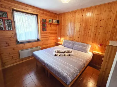 a bedroom with a bed with wooden walls and a window at Fior di Larice - Alpine Stay Apartments in Ziano di Fiemme