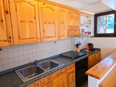 a kitchen with wooden cabinets and a sink at Fior di Larice - Alpine Stay Apartments in Ziano di Fiemme