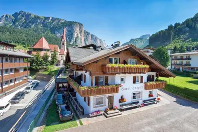 a building in a town with mountains in the background at Garni Crepaz in Selva di Val Gardena