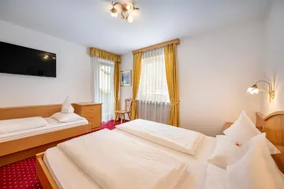 a hotel room with two beds and a television at Garni Crepaz in Selva di Val Gardena