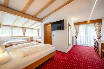 two beds in a hotel room with red carpet at Garni Crepaz in Selva di Val Gardena
