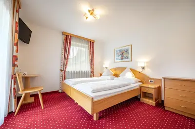 a bedroom with a bed and a desk and a window at Garni Crepaz in Selva di Val Gardena