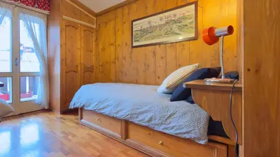 a bedroom with a bed and a desk with a lamp at Homeby, Casa Due Vette in Cortina dʼAmpezzo