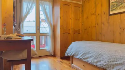 a bedroom with a bed and a desk and a window at Homeby, Casa Due Vette in Cortina dʼAmpezzo