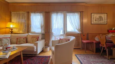 a living room with a white couch and some windows at Homeby, Casa Due Vette in Cortina dʼAmpezzo
