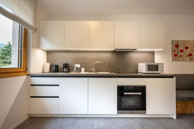 a kitchen with white cabinets and a sink and a microwave at Apartments No 10 in Ponte Gardena