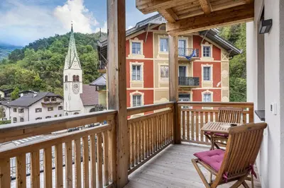 a balcony with a table and chairs and a church at Apartments No 10 in Ponte Gardena