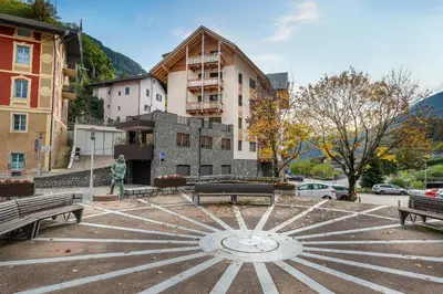 a statue in a park with benches and a building at Apartments No 10 in Ponte Gardena
