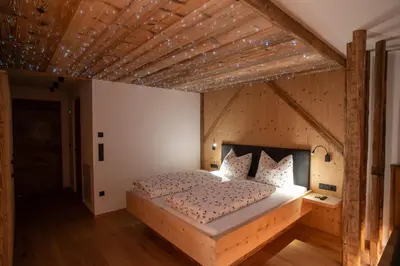 a bedroom with a large bed with a wooden ceiling at Lanzenschuster in San Genesio Atesino