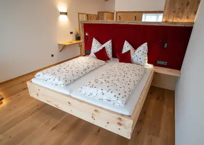 a bedroom with a wooden bed with a red headboard at Lanzenschuster in San Genesio Atesino