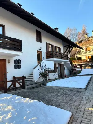 a white house with snow in front of it at Appartamento Dolomiti in Castello di Fiemme