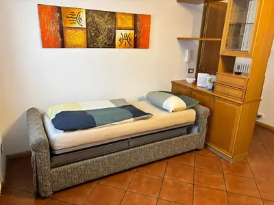 a bed sitting in a room with a dresser at Appartamento Dolomiti in Castello di Fiemme