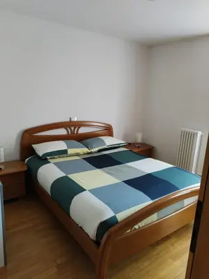 a bedroom with a bed with a blue and white comforter at Appartamento Dolomiti in Castello di Fiemme