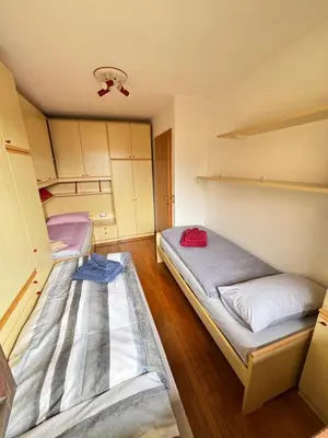 two beds in a small room with cabinets at Appartamento Dolomiti in Castello di Fiemme